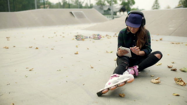 Girl wearing rollerblades and listening music in skatepark, steadycam shot
