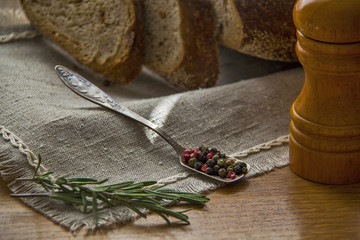 Spices - Rosmary and pepper on the table with pepper mill and bread