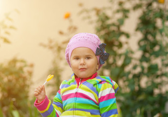 Little girl eats sweet yellow candy.