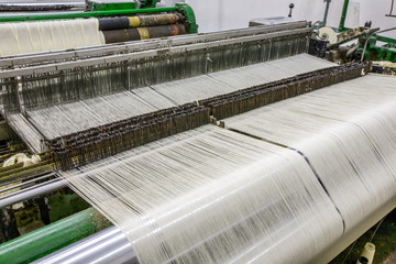 A modern textile factory interior with metallic machines weaving cotton fabric, showcasing the advanced technology in the industry.