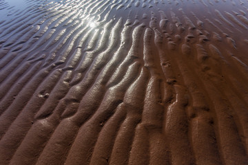 rippled red sand at low tide with sun reflection; Prince Edward Island, Canada