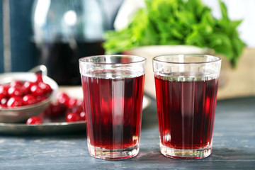 Sweet homemade cherry juice on table, on color wooden background