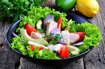 Healthy salad of avocado, tomatoes, canned tuna, onions and lettuce with parmesan, parsley and olive oil