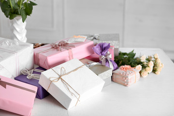Composition of cute gift boxes and roses on white table