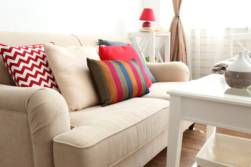 Room interior with comfortable sofa and colourful pillows, blurred