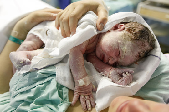 Mother hugging a vernix covered newborn