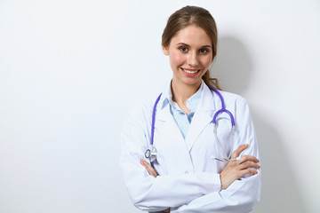 Friendly smiling young female doctor, standing near wall