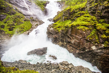Kjosfossen waterfall in Flam, Norway. Kjosfossen waterfall is one of the most visited tourist attractions in Norway. Its total fall is around 225 metres (738 ft).