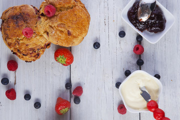 scones raspberries jam and cream shot from above on wooden boards portrait