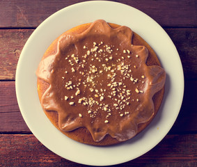 Pumpkin cake with caramel and peanuts on wooden table