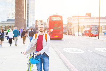 Hipster man walking on London bridge and holding his fixed gear - obrazy, fototapety, plakaty
