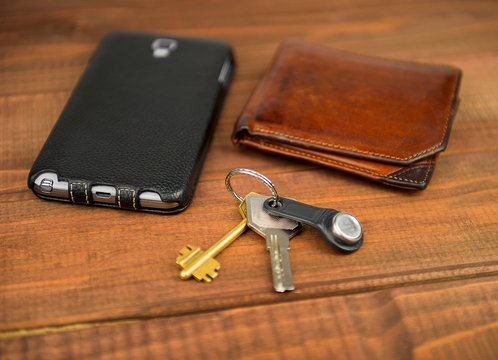 Leather purse, phone pouch and keys on a wooden table background