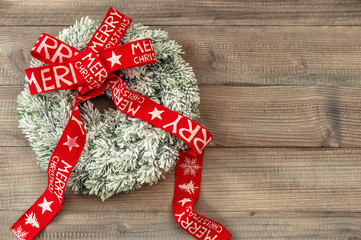 Christmas wreath with red ribbon on wooden background