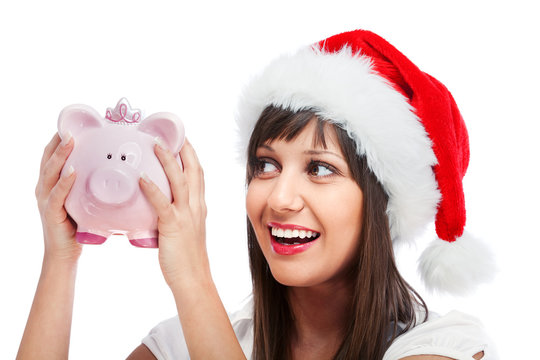 Young woman with santa cap holding piggy bank