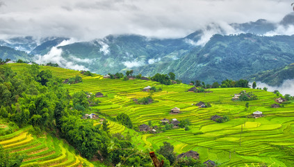 A corner of the hill villages of Ha Giang with clouds covering the mountain permissive and small houses on the terraces in the afternoon sun picture letter most beautiful country I've ever seen