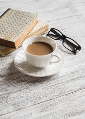 Books, glasses and coffee cup on bright wooden surface