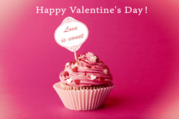 Delicious cupcake with inscription on pink background