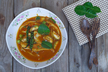 Spicy fish curry in bowl with fork and spoon