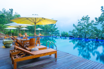 Umbrella chair in hotel pool resort with sunset