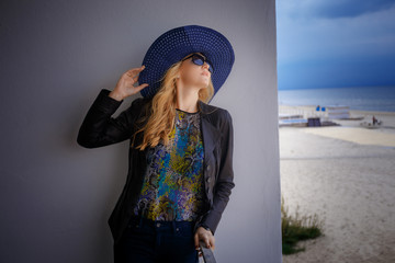 Blond woman in sunglesses and blue summer hat.