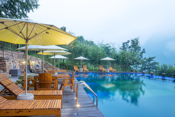Umbrella chair in hotel pool resort with sunset
