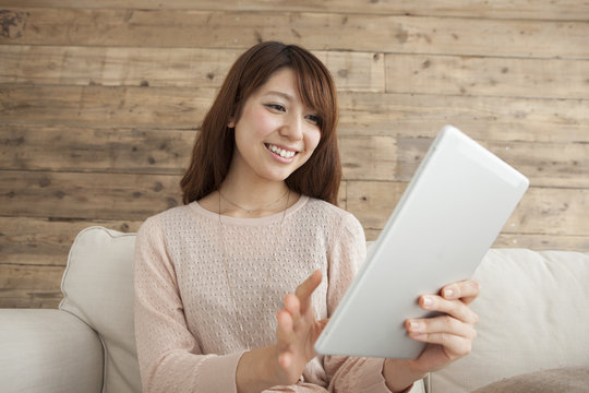 Young women are reading e-books sitting on the sofa