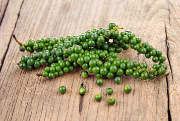 Green peppercorns on wooden background.