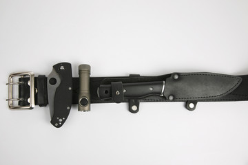 two knives and a flashlight attached to a black leather strap