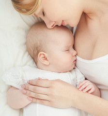 Young mother and her baby, sleeping in bed. Mother and baby. Hap