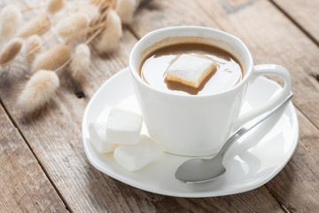 Cup of coffee with marshmallow on a wood table. Selective focus.