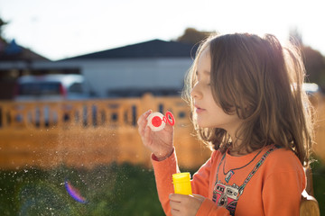 Cute little girl making soap bubbles in the garden