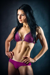 Fototapeta na wymiar Muscular young woman athlete portrait over dark background