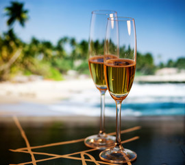 Champagne glasses on tropical beach at sunset - exotic New Year
