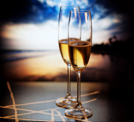 Champagne glasses on tropical beach at sunset - exotic New Year