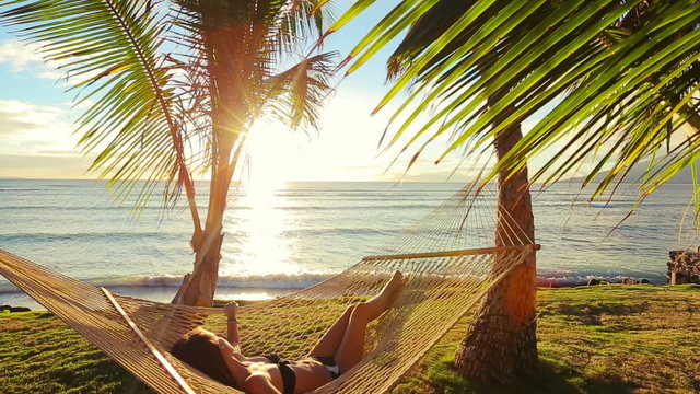 Beautiful Young Woman Relaxing in Tropical Hammock at Sunset. Bikini Summer Vacation.
