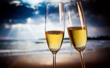 Champagne glasses on tropical beach at sunset - exotic New Year