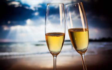 Champagne glasses on tropical beach at sunset - exotic New Year