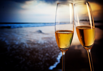 Champagne glasses on tropical beach at sunset - exotic New Year