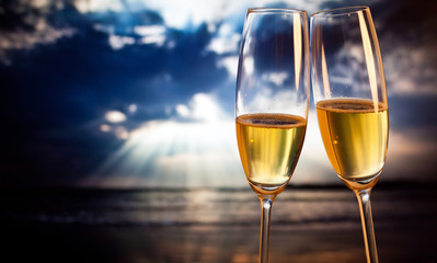 Champagne glasses on tropical beach at sunset - exotic New Year