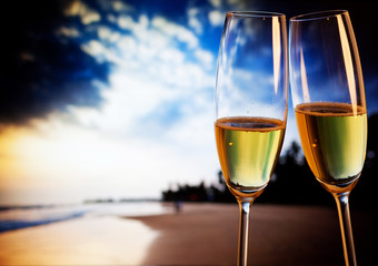 Champagne glasses on tropical beach at sunset - exotic New Year