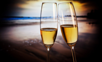 Champagne glasses on tropical beach at sunset - exotic New Year