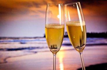 Champagne glasses on tropical beach at sunset - exotic New Year