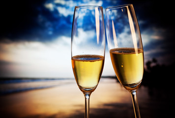 Champagne glasses on tropical beach at sunset - exotic New Year