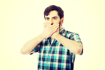 Young shocked man covering his mouth.