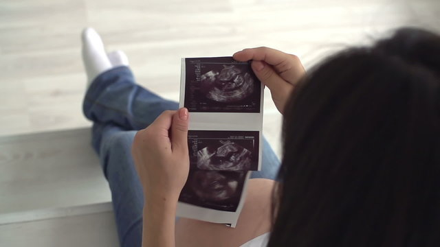 pregnant girl a great time looking at the ultrasound printed on paper,close up