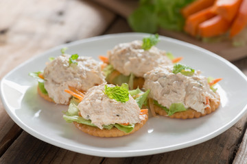 Crackers with tuna salad on white palte.