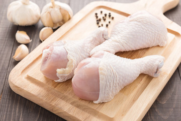 Ingredients and raw chicken drumsticks on cutting board on wood