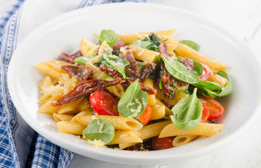 Pasta with sun dried tomato on a white plate.