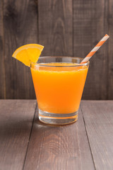 Glass of fresh orange juice on wooden table