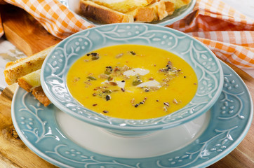 Bowl of pumpkin soup with bread crouton.